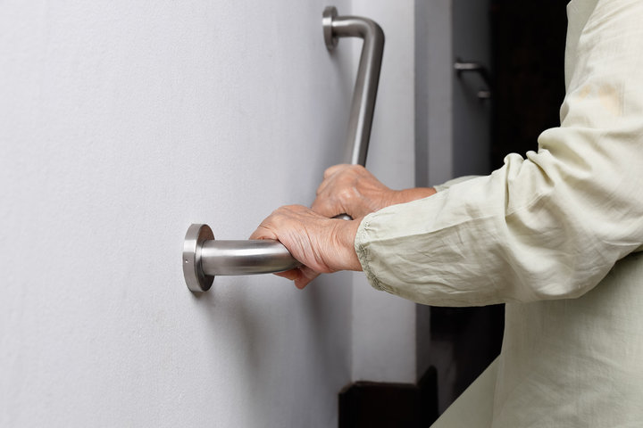 older person hanging on to a support railing 