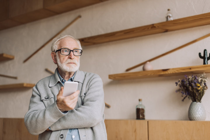 older man looking lonely with his mobile phone